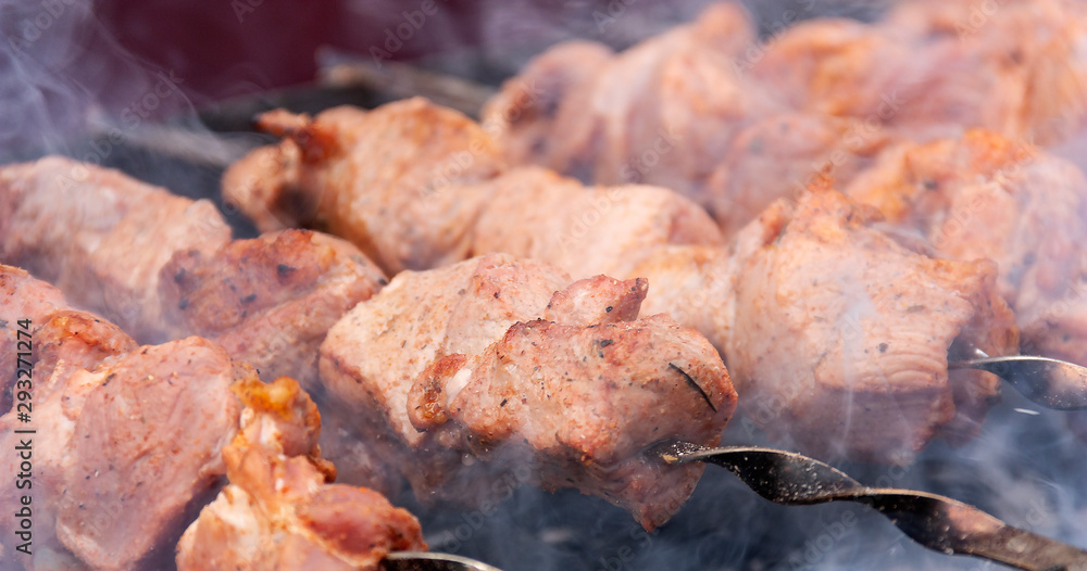 skewers of meat with smoke is cooking on the coals skewers of meat with smoke is cooking on the coals