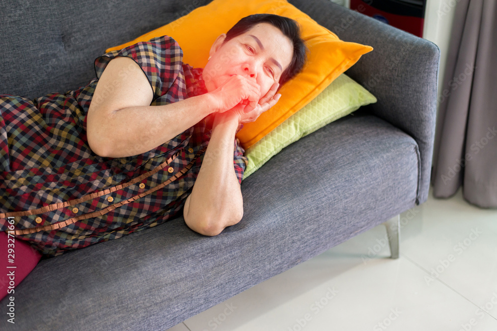 Foto de Elderly Asian woman coughing and lying on sofa at home,Female