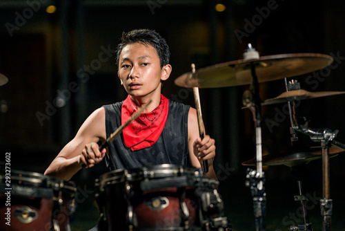 Asian American mixed teenager playing drums at home garden . cool and handsome young boy practicing on drum kit rehearsing passionate in badass rock band look