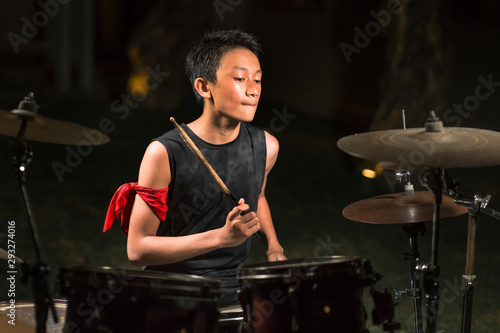 Valokuva Asian American mixed teenager playing drums at home garden
