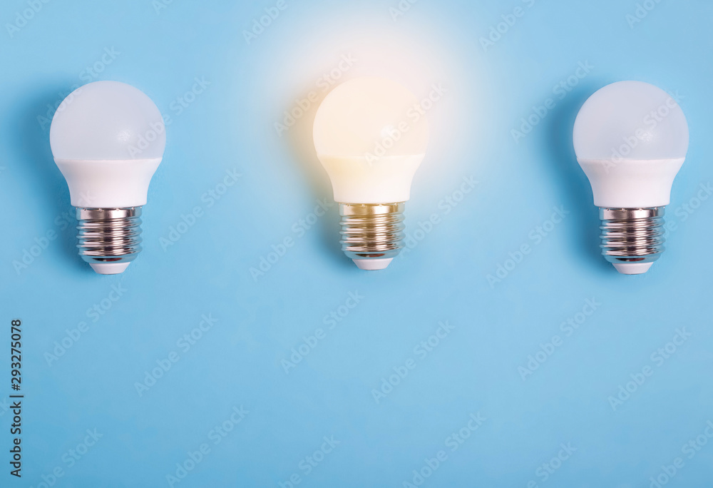 three led light bulbs on blue background one light bulb is lit