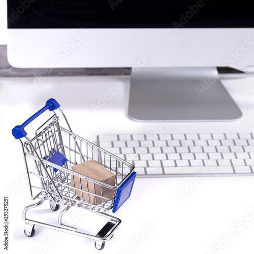 concept of online shopping box in shopping cart and computer on white background