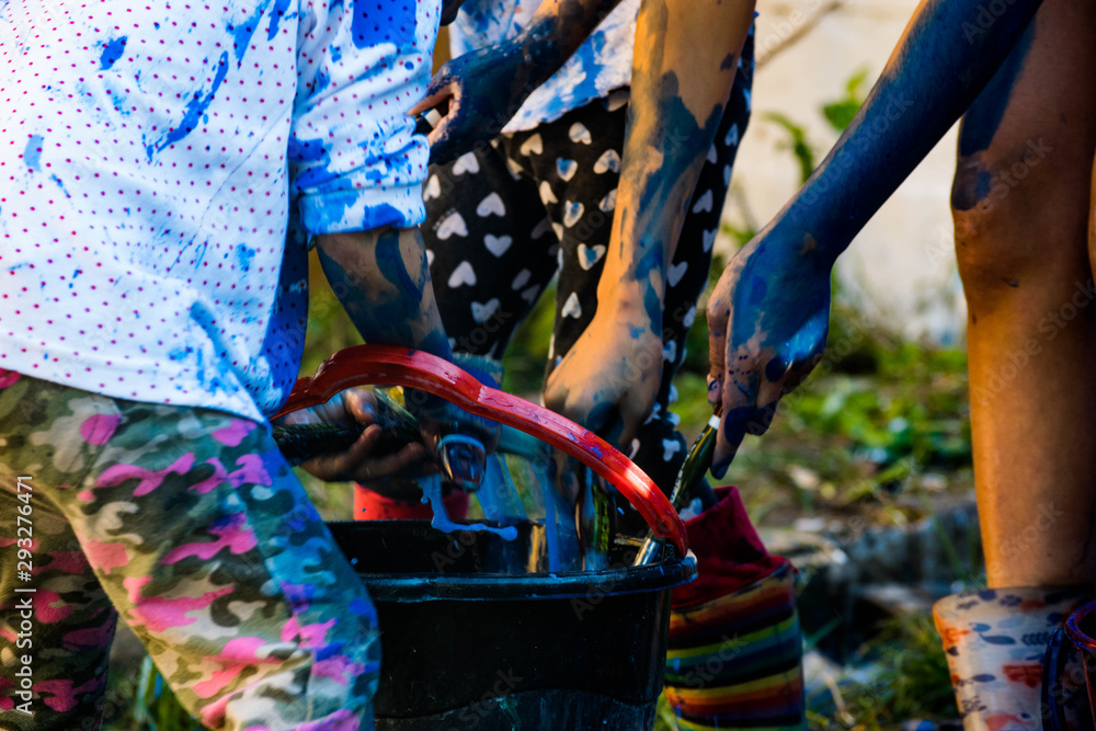 Obraz premium Children hands cleaning blue brushes in a bucket
