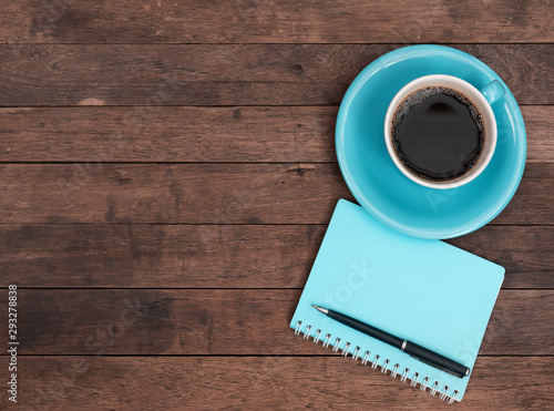 Blue coffee cup,pen and notebook on grunge wooden table top background,top view with copy space