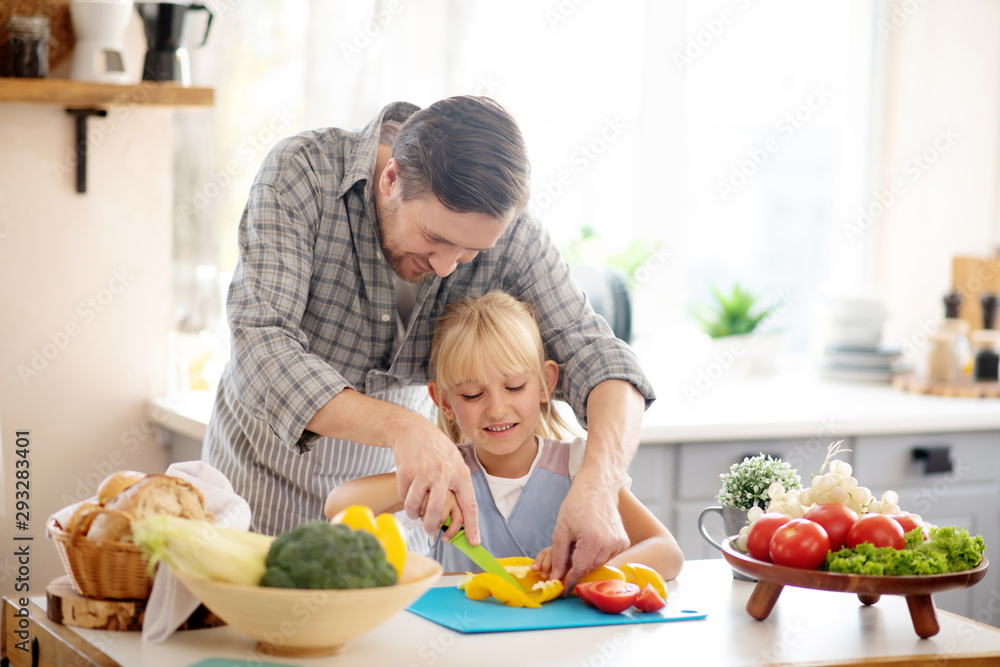 Father and daughter slicing peppers before making stew Father and daughter slicing peppers before making stew