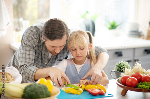 Handsome daughter assisting daughter while cutting vegetables