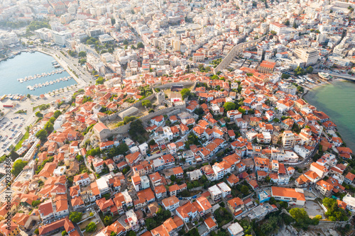 Aerial view of a slide with a drone on a panorama of buildings of residential and administrative houses of the city of Kavala in Greece at dawn. Roof plan from a bird's eye view. Sea. Fortress. Sunset