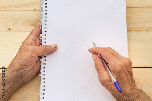 Hands of an elderly man hold a notebook and pen. The concept of writing memoirs, old age and memories. Image.