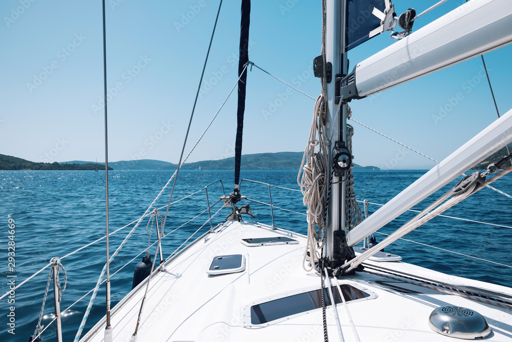 Bow of the yacht and yacht equipment. The texture of the masts and ropes on a background of mountain peaks, blue sea and blue sky on a sunny day in summer. Details of sailing equipment. Tourism Bow of the yacht and yacht equipment. The texture of the masts and ropes on a background of mountain peaks, blue sea and blue sky on a sunny day in summer. Details of sailing equipment. Tourism