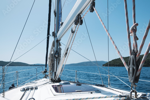Bow of yacht and yacht equipment. The texture of the masts and ropes on a background of mountain peaks, blue sea and blue sky on a sunny day in summer. Details of sailing equipment. Tourism. Travel © marina_larina