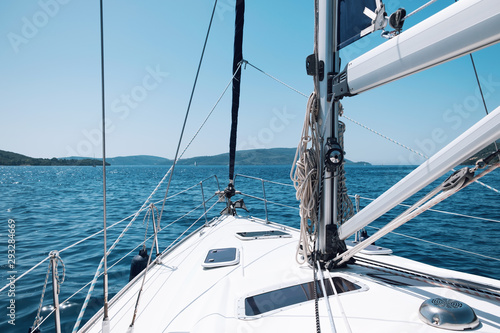 Bow of the yacht and yacht equipment. The texture of the masts and ropes on a background of mountain peaks, blue sea and blue sky on a sunny day in summer. Details of sailing equipment. Tourism