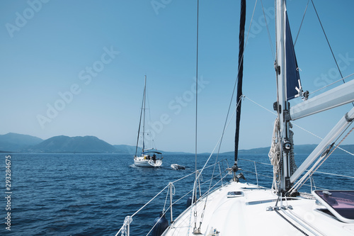 Bow of the yacht and yacht equipment. The texture of the masts and ropes on a background of mountain peaks, blue sea and blue sky on a sunny day in summer. Details of sailing equipment. Tourism