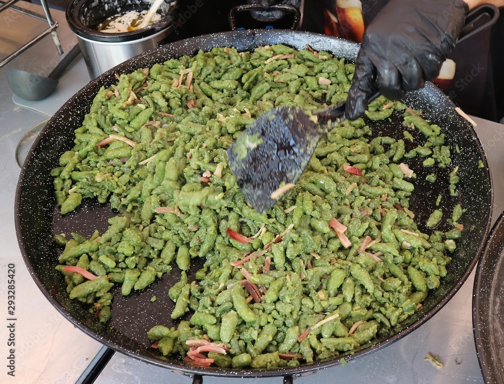 Chef cooking Spatzle with cream and speck, a typical dish of German speaking populations It's a soft egg noodle with spinach Chef cooking Spatzle with cream and speck, a typical dish of German speaking populations It's a soft egg noodle with spinach