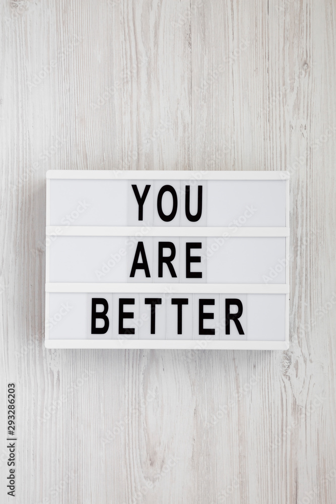 'You are better' words on a lightbox over white wooden surface, top view. Overhead, from above. Flat lay.