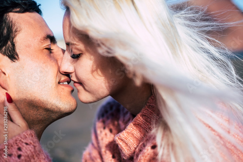 Romantic close up portrait of yong people kissing and enjoying love together - blonde caucasian girl and handsome boy with. closed eyes and close lips