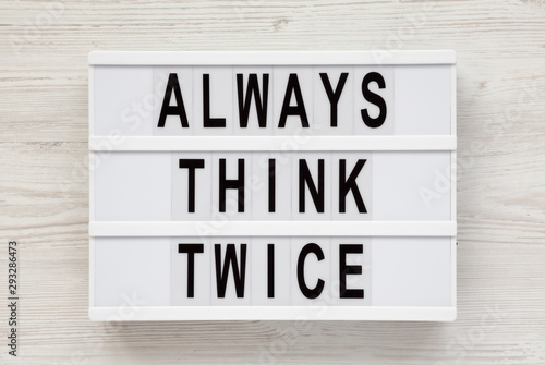'Always think twice' words on a lightbox on a white wooden surface, top view. Overhead, from above, flat lay.