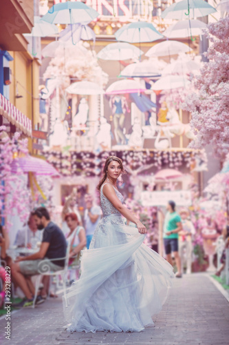 beautiful bride in a light grey luxurious wedding dress in a street with rose flowers