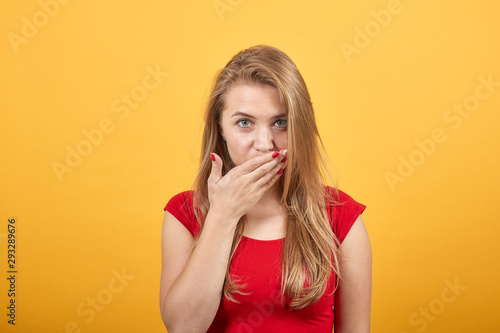 young blonde girl in red t-shirt over isolated orange background shows emotions