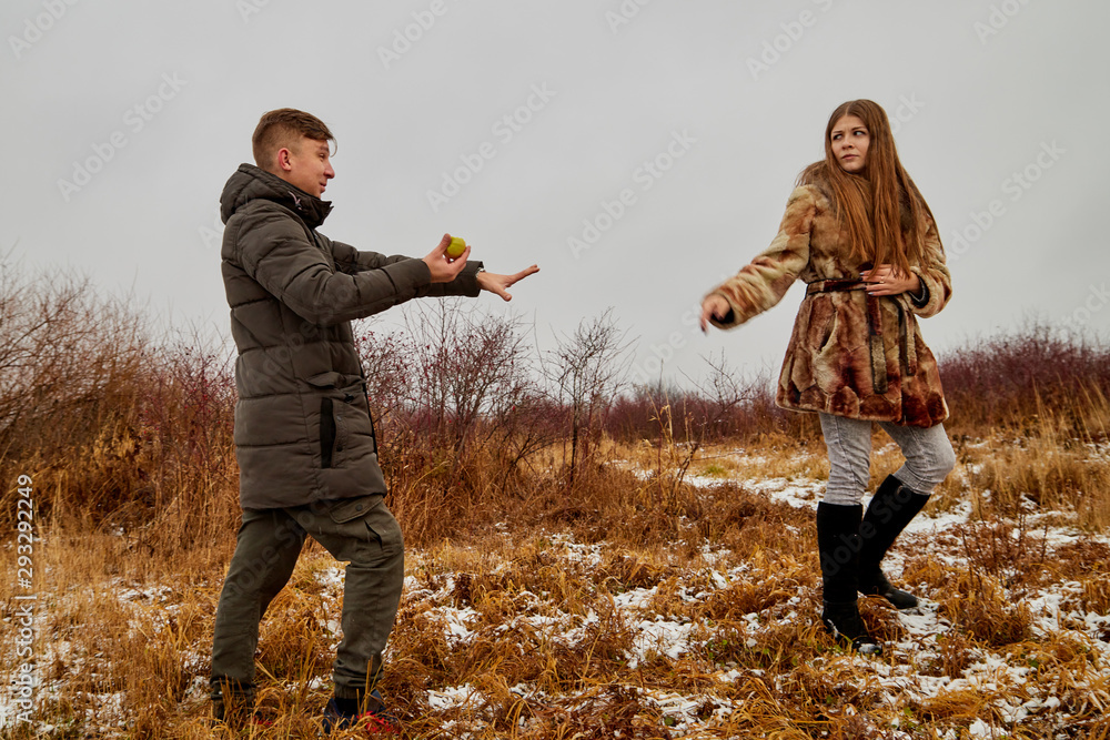 Couple in love on autumn or winter walk near lake with apple