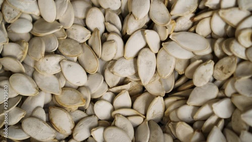 Pumpkin seed closeup rotating against background in grocery 4K. Vegan seed spining showing presentation. Pampkin background turning beautifully for buyer. Clear place for your isolated text pattern photo