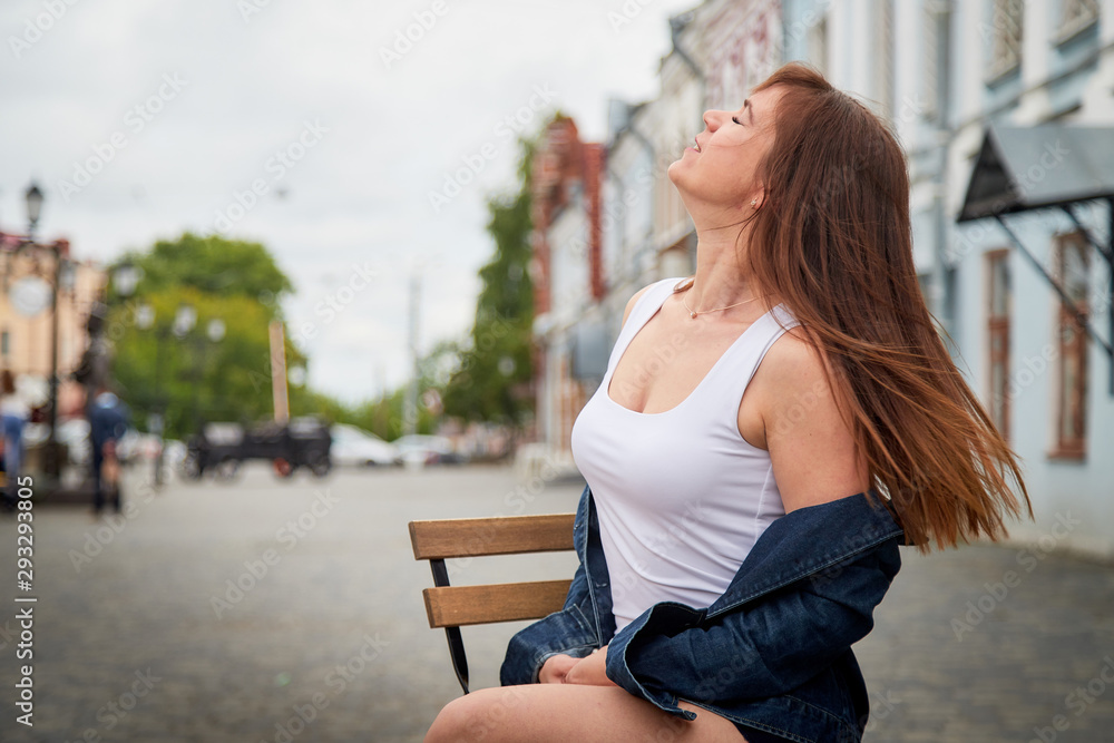 Brunette funny pretty girl sitting on chair in Central part of old city. Walk in downtown. Portrait of girl on street Brunette funny pretty girl sitting on chair in Central part of old city. Walk in downtown. Portrait of girl on street