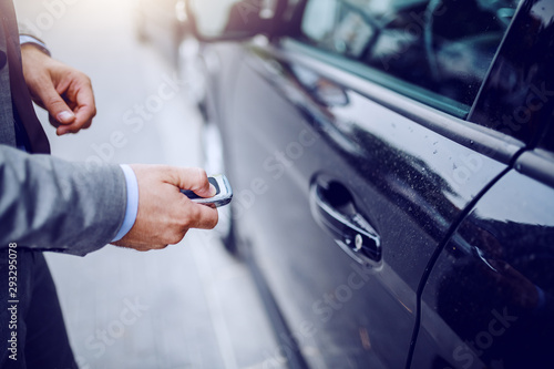 Obraz na plátně Close up of man unlocking his car on rainy weather.