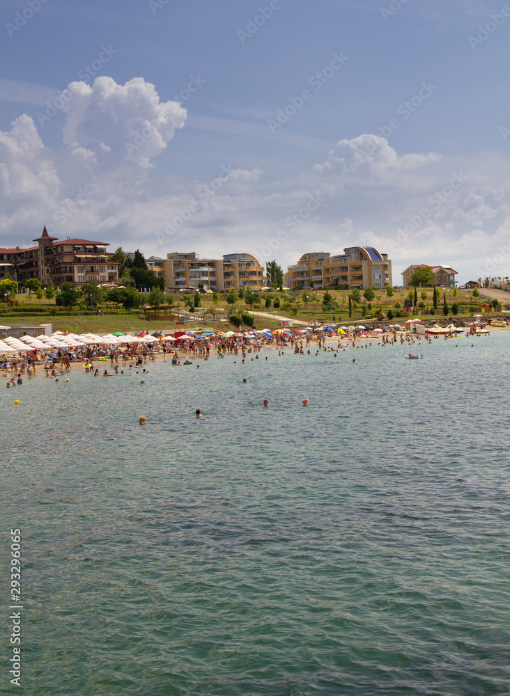 Vertical photo of a black sea beach with vacationers