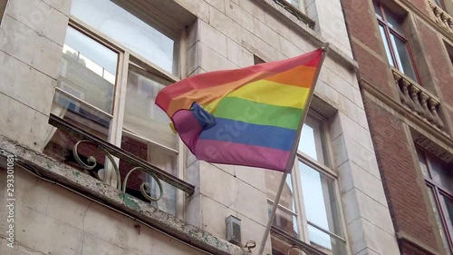 Gay pride LGBT rainbow flag waves on an urban city apartment building