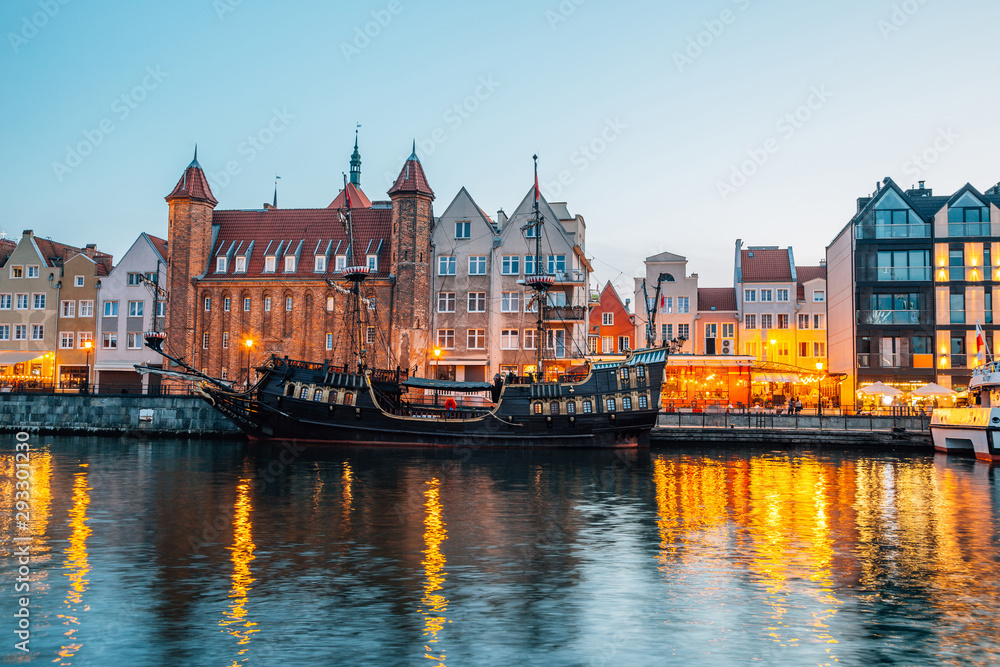 Old town buildings and Straganiarska Gate with river at night in Gdansk, Poland