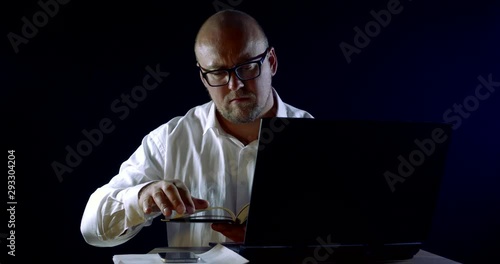 male office worker is looking for notes in datebook and calling, sitting in front of notebook photo