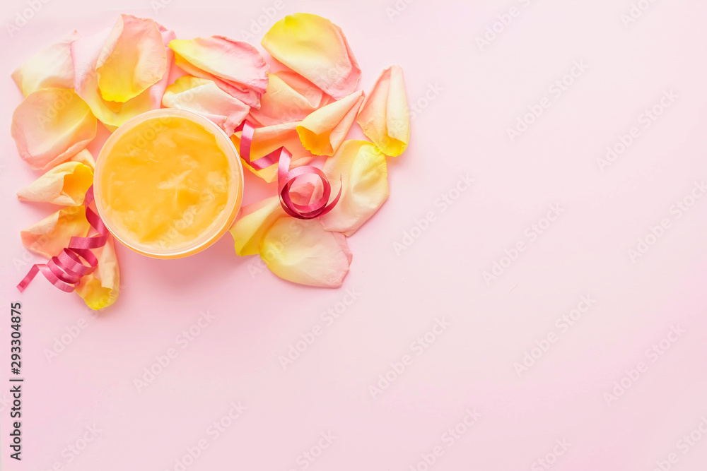 Open jar of cosmetic cream and rose petals on pink background. Concept of organic spa cosmetics. Flat lay, top view, copy space.