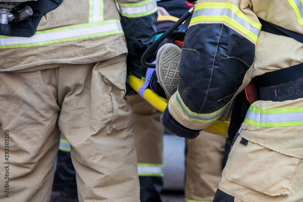  professional firefighter firefighters fireproof suits, white helmets and gas masks carry the injured person on stretchers