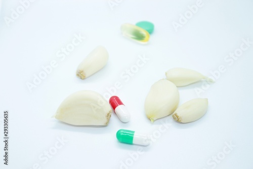 Peeled garlic and vitamins located on a white background
