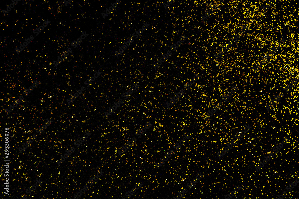 Golden glitter scattered on the black card background, top view, selective focus