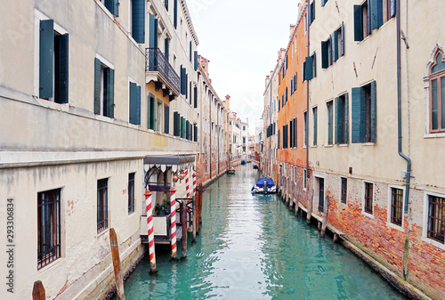 One of the channels in Venice between old houses and a bridge in the distance © Alex_Po
