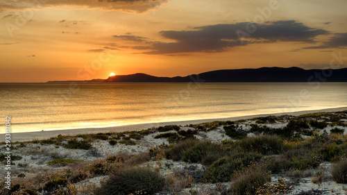 Troia, Portugal - September 13, 2019: Sunset over the Troia peninsular from Praia da Malha da Costa with a view towards Cabo Espichel and the Arrabida mountains, Portugal