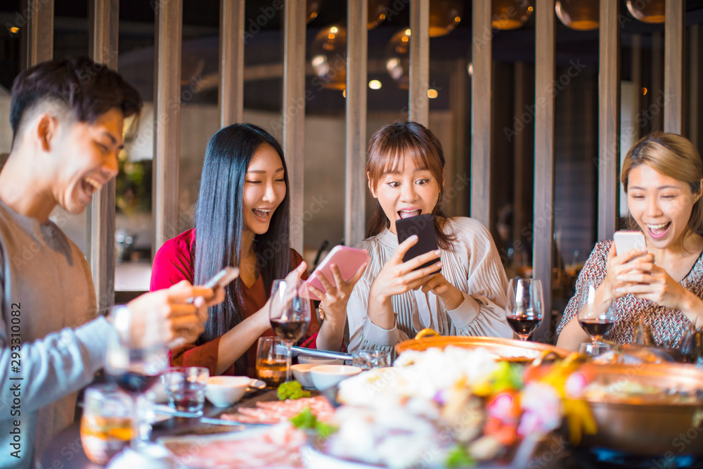 Group of friends having fun at the restaurant and looking at smart phone Group of friends having fun at the restaurant and looking at smart phone