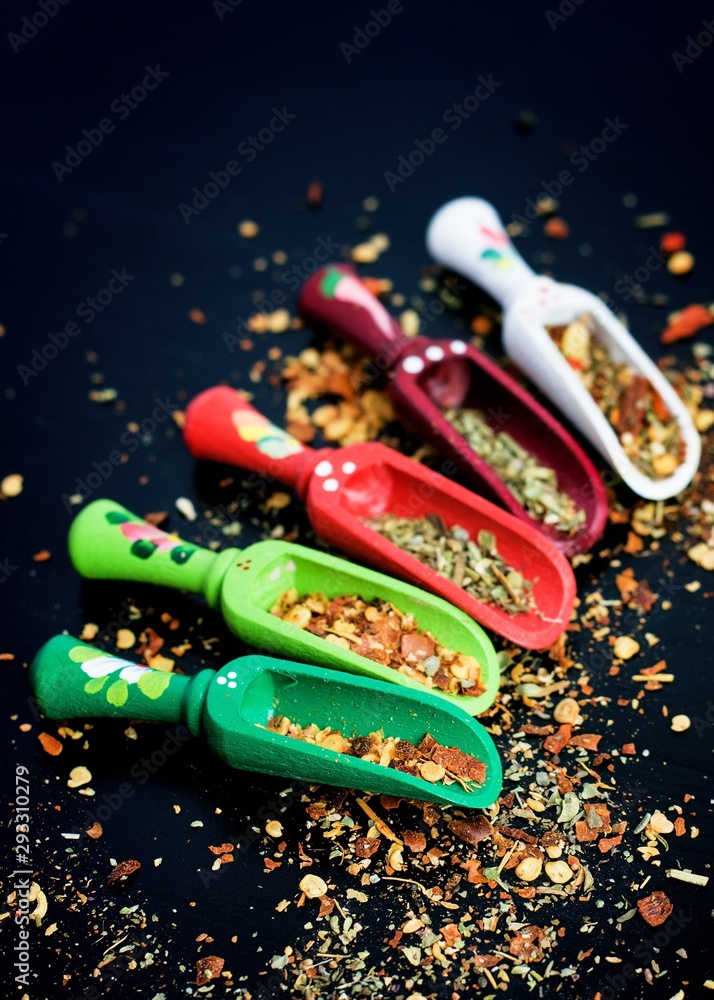 Spices and wooden spoons on black Spices and wooden spoons on black