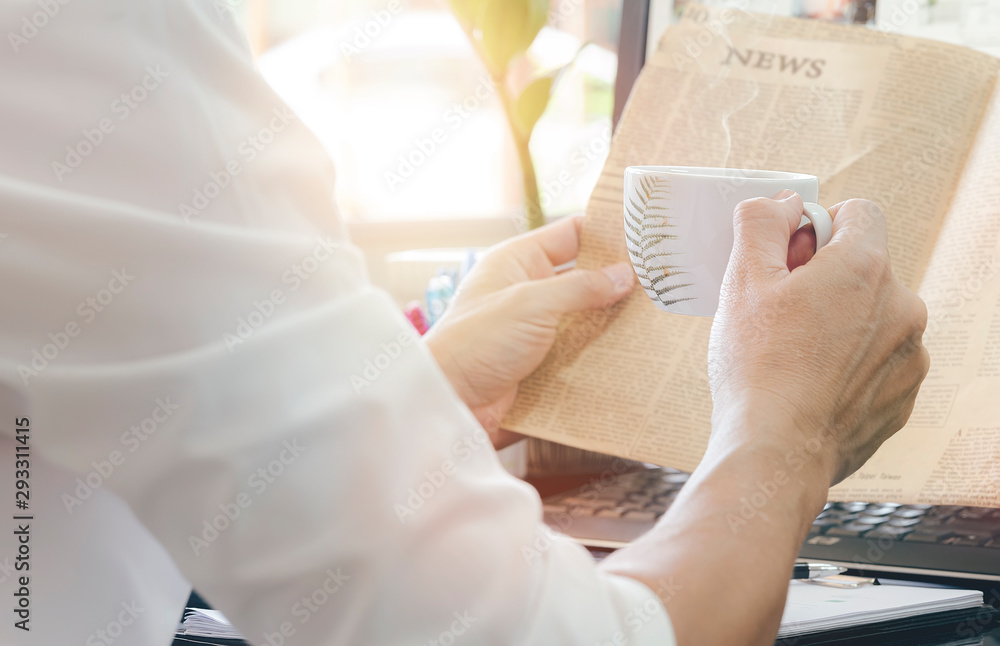 Obraz premium man with cup of coffee reading newspaper while take a break in modern office.