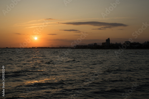 Atardecer en Santa Pola  Alicante  Espa  a. Primer plano de mar con reflejos de sol y horizonte de cielo naranja con nubes