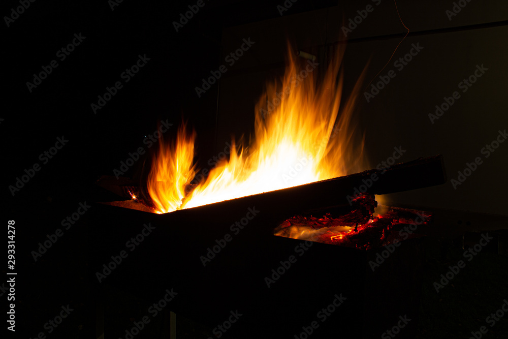 Fototapeta premium The fire burns in the grill at night. bright fire, wood. the flames on the night