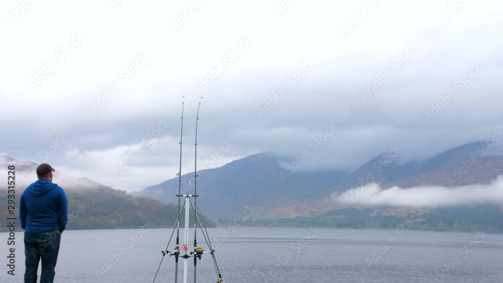 4K fisherman on lake side in the Scottish Highlands. Man fishing on a grass bank with a mountain and cloud horizon in rural Scotland. 4K fisherman on lake side in the Scottish Highlands. Man fishing on a grass bank with a mountain and cloud horizon in rural Scotland.