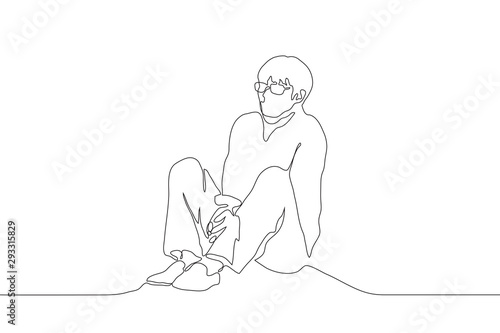 A continuous line of art man with glasses sits alone on the floor, clenching his shoulders and holding his hands together between his legs. The concept of loneliness. Can be used for animation