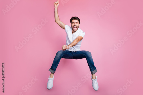 Full length photo of crazy active middle eastern guy cowboy concept ride fast derby horse on prairie jump scream shout feel rejoice wear stylish trendy clothes sneakers isolated pink color background
