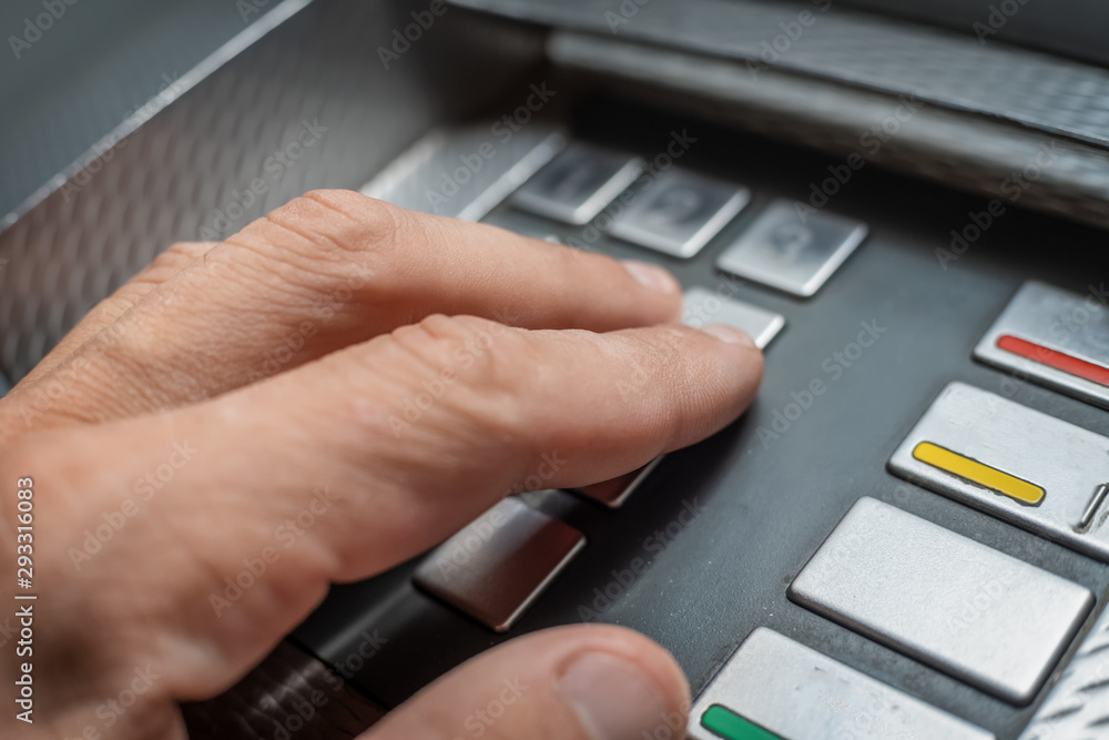Men's hand presses the buttons of the ATM to enter the pin code close-up. Photo at night Men's hand presses the buttons of the ATM to enter the pin code close-up. Photo at night