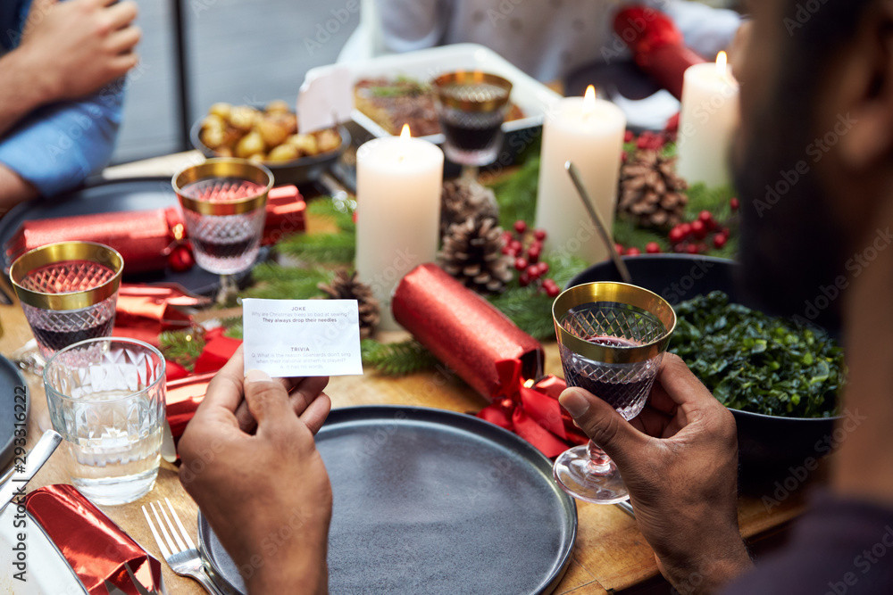 Group Of Friends Sitting Around Table At Home For Christmas Dinner