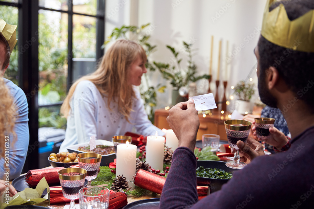 Group Of Friends Sitting Around Table At Home For Christmas Dinner