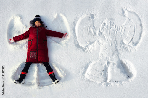 The girl lies in the snow and makes a snow angel photo