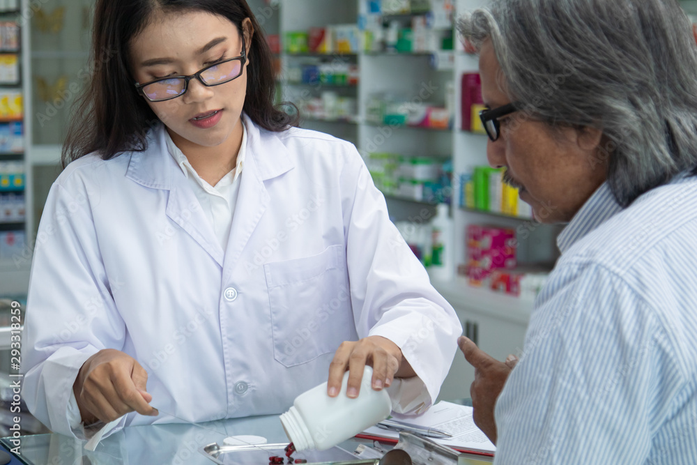 Young Asian attractive female pharmacist explaining details information of medicine products, pharmacist pay attention listen illness client male, giving prescription to senior apothecary senior man Young Asian attractive female pharmacist explaining details information of medicine products, pharmacist pay attention listen illness client male, giving prescription to senior apothecary senior man