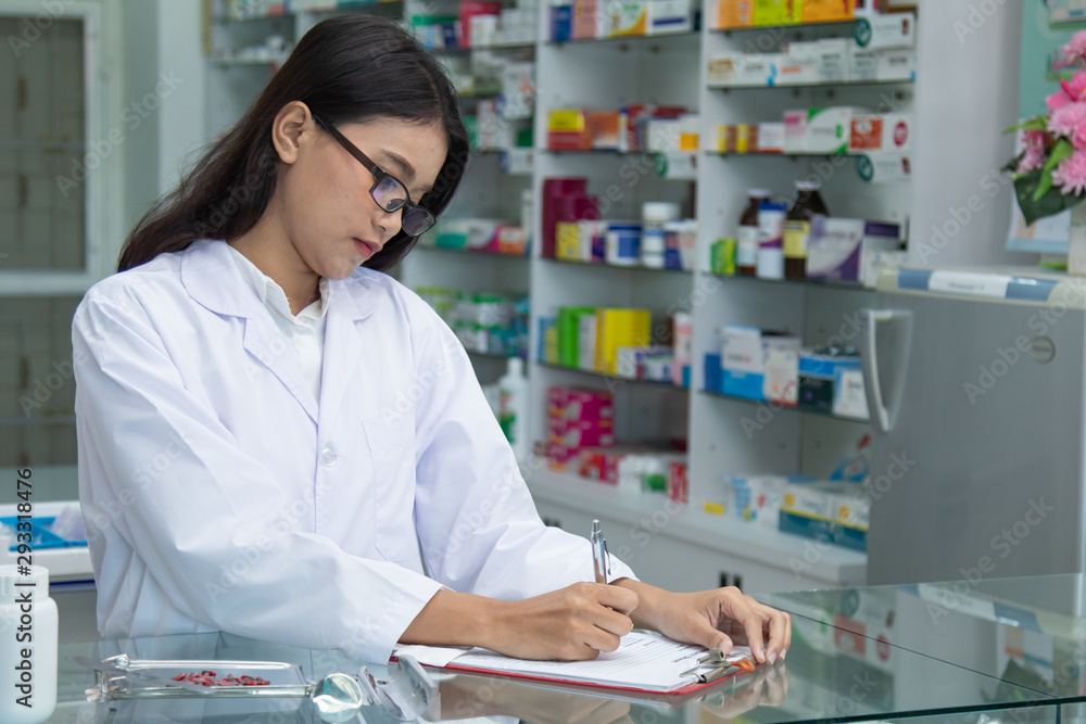 Young Asian attractive female pharmacist explaining details information of medicine products, apothecary pay attention to record selling transaction sick symptom , giving prescription to customer